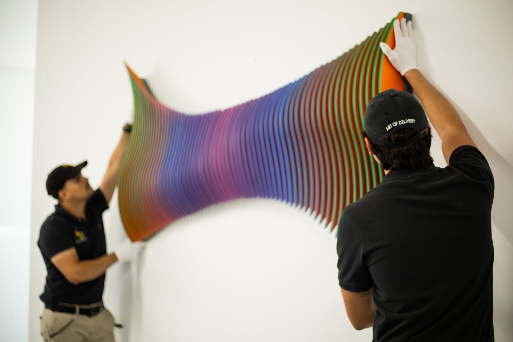 Two specialists installing a kinetic wall sculpture