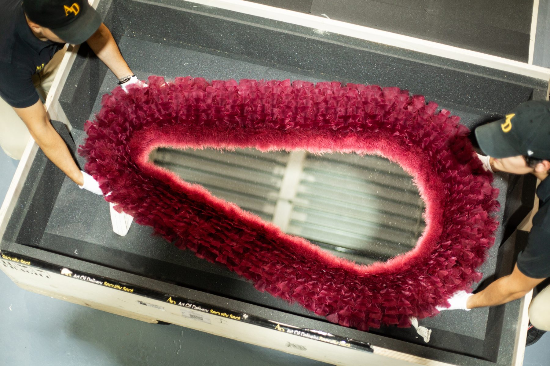 Two specialists packing a feather-framed mirror into a custom crate